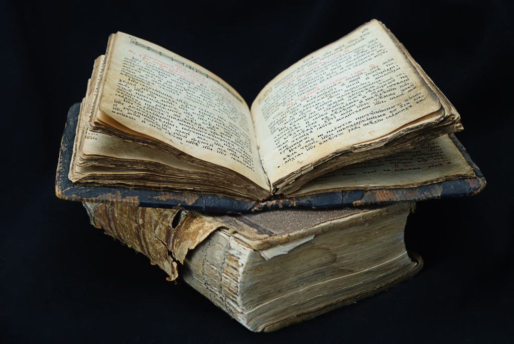 A pile of old books with the top one left open.