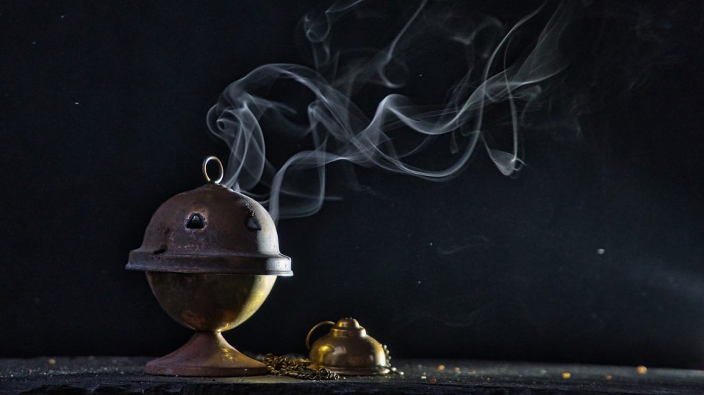 Upon a black background, a lone censer sits, smoking faintly.