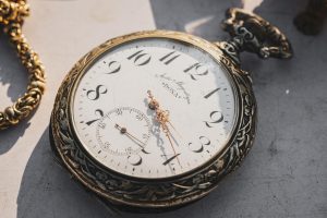 An old watch sits against a grey background.