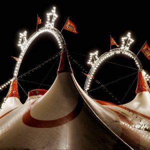 The outside of a circus tent illuminated at night.