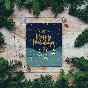 A holiday card with Happy Holidays written upon it, surrounded by firs