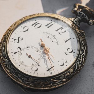 An old watch sits against a grey background.