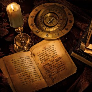 An old open book accompanied by a compass and a candle